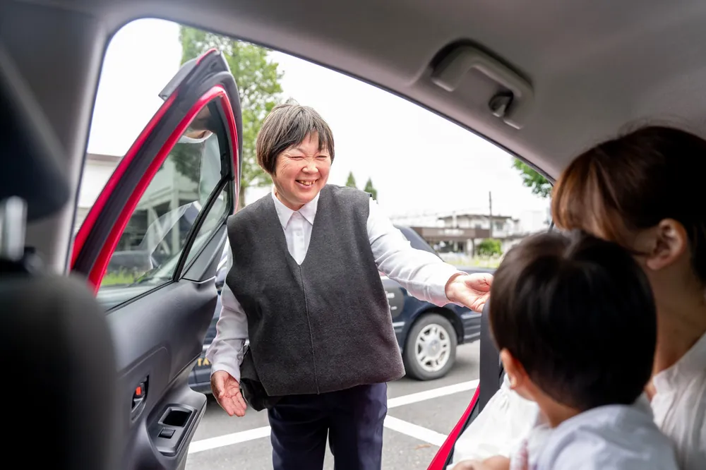 笑顔で親子を車内に迎える女性ドライバー